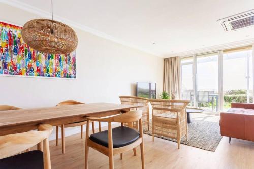 a living room with a wooden table and chairs at Dolphin Beach cabana Luxe beach cabana voor 4 personen direct aan het strand in Table View
