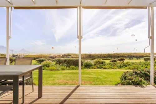 a patio with a table and a view of a field at Dolphin Beach cabana Luxe beach cabana voor 4 personen direct aan het strand in Table View