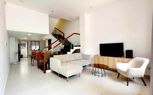 a living room with white furniture and a tv at Hue House Stay in Thôn Trường Giang