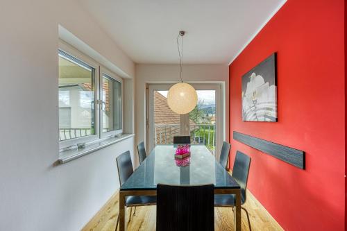 a dining room with a red wall and a table and chairs at Honeycomb Chalets And Apartments Mozirje in Mozirje