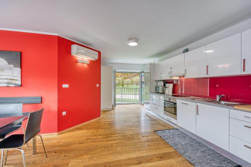 a kitchen with red walls and white cabinets and a table at Honeycomb Chalets And Apartments Mozirje in Mozirje
