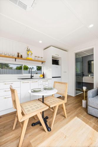 a white kitchen with a table and two chairs at Casa De Limon in Ballarat