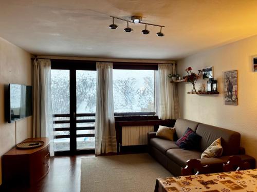 sala de estar con sofá y ventana grande en Cervinia Ski In Ski Out - Spacious Apartment en Breuil-Cervinia