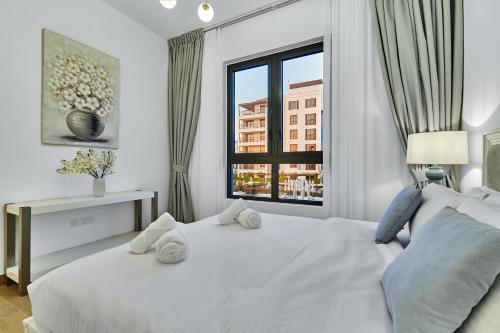 a bedroom with a large white bed with a window at Majestic La MER La Voile1 - Jumeirah 1- Swimming pool view in Dubai