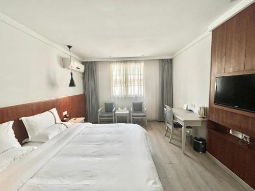 een hotelkamer met een bed, een bureau en een televisie bij Tianshui Times Hotel Zhangjiagang in Zhangjiagang