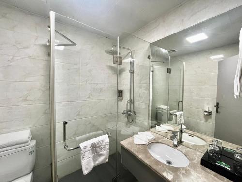 a bathroom with a shower and a sink and a toilet at Tianshui Times Hotel Zhangjiagang in Zhangjiagang