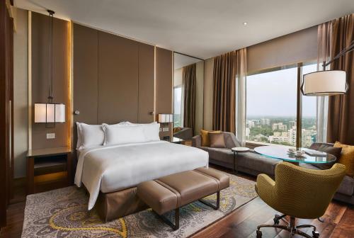 a bedroom with a bed and a living room at Conrad Pune in Pune