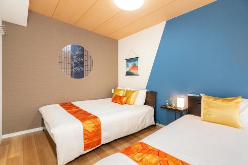 東京的住宿－KYARA Hotelミスミ301，蓝色墙壁客房的两张床