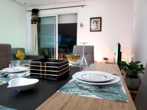 - une table à manger avec des assiettes au-dessus dans l'établissement Stylish & homely 3 fresh beds & pool view, à Marrakech