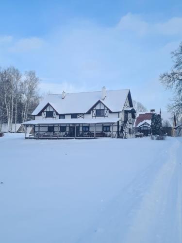 a house with snow on the roof at Zirgu sēta "Klajumi" - Horse ranch "Klajumi" in Kaplava