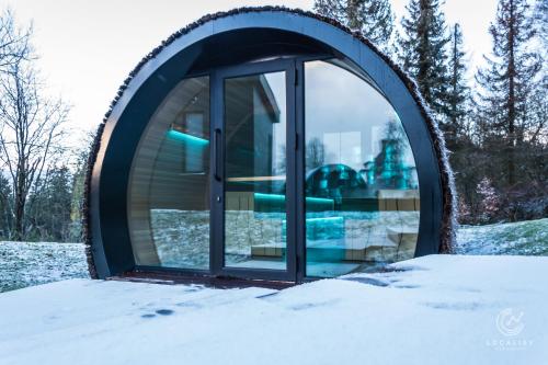 un bâtiment circulaire avec une porte en verre dans la neige dans l'établissement Domaine Des Hautes Fagnes, à Ovifat