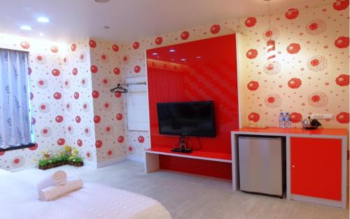 a room with a tv and a red wall at Neo Sky Hotel in Kaohsiung