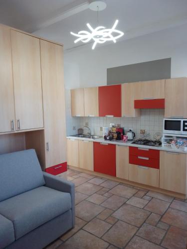 a kitchen with red cabinets and a couch in a room at Lovely apartment with terrace by Alterego in Villanova dʼAsti