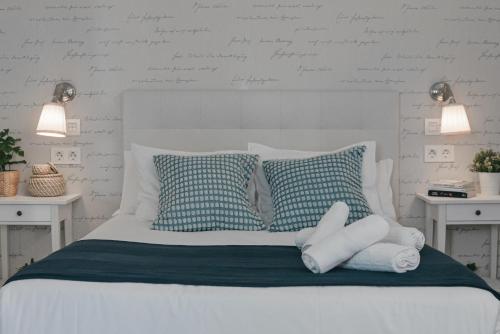 a white bed with blue and white pillows on it at Larios Premium Apartments in Málaga