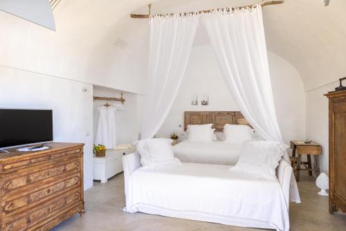 a white bedroom with two beds and a television at Masseria Le Torri in Polignano a Mare
