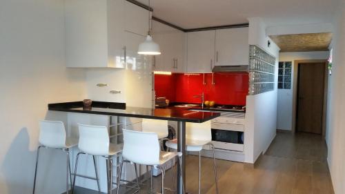 a kitchen with red and white cabinets and white stools at The Sun House in Santa Iria da Azóia