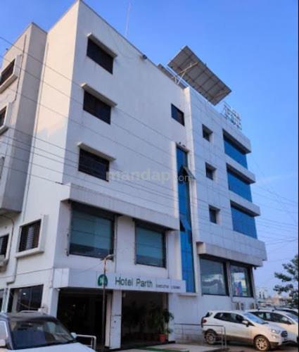 un edificio blanco con coches estacionados frente a él en HOTEL PARTH EXECUTIVE, en Lātūr