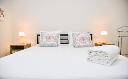 un letto bianco con cuscini e asciugamani di Modern apartment Dora a Mendrisio