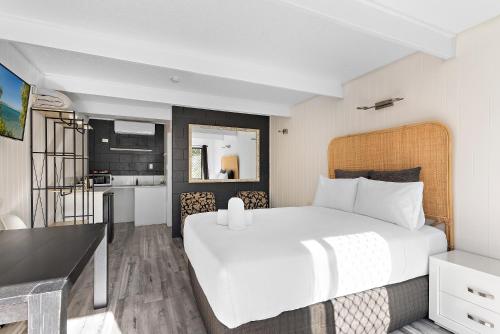 a bedroom with a large white bed and a kitchen at Buderim Fiesta Motel in Tanawha