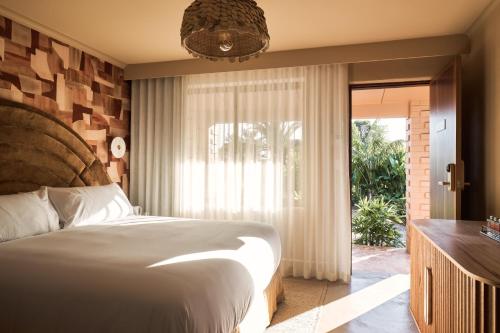 1 dormitorio con 1 cama y puerta corredera de cristal en Swell Hotel Byron Bay - Adults Only, en Byron Bay