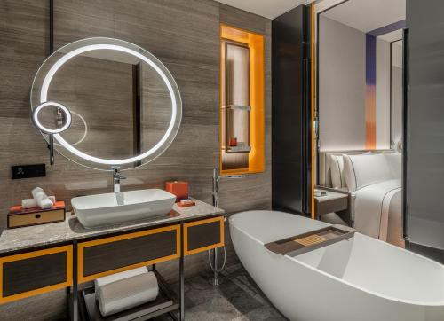 a bathroom with a tub and a sink and a mirror at Canopy by Hilton Xi'an Qujiang in Xi'an