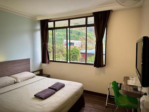 a bedroom with a bed and a large window at Parkland Hotel in Brinchang