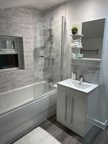 a bathroom with a tub and a sink and a shower at 2 bedroom modern flat in Romsey in Romsey