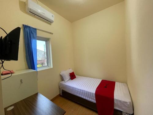 a small bedroom with a bed and a tv at RedDoorz at Ramelau near AP Pettarani in Makassar