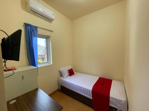 a small bedroom with a bed and a tv at RedDoorz at Ramelau near AP Pettarani in Makassar