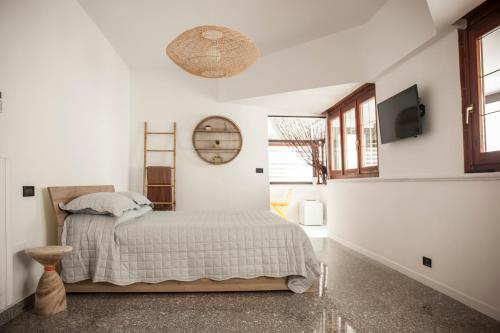 a white bedroom with a bed and a tv at Live and Love Italy in Monopoli