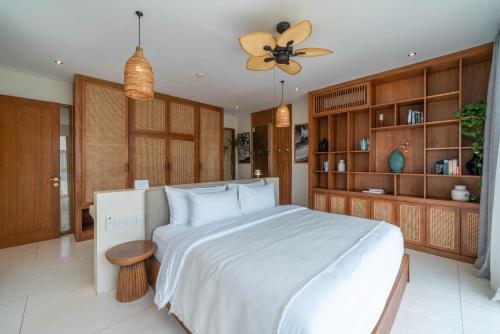 a bedroom with a large white bed and a fan at Alegria de la Vida in Canggu