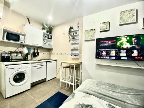 マドリードにあるAcogedor apartamento en el Centro de Madridのキッチン(洗濯機付)、壁掛けテレビが備わります。