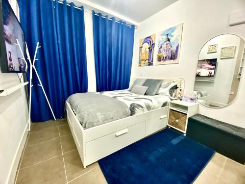 a bedroom with blue curtains and a bed with a mirror at Acogedor apartamento en el Centro de Madrid in Madrid