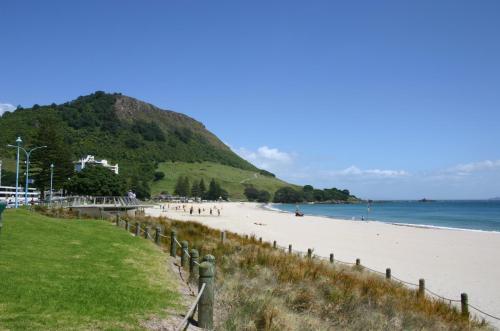 a beach with people walking on the sand and the ocean at Kereru Cottage in Whakamarama