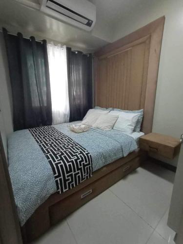 a bedroom with a large bed with a wooden headboard at Cozypura Staycation at S Residences Mall of Asia Complex Pasay City in Manila