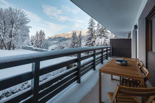 einen Balkon mit einem Tisch und Blick auf schneebedeckte Bäume in der Unterkunft Flat - Le Whivern A stone's throw from the village centre in Megève