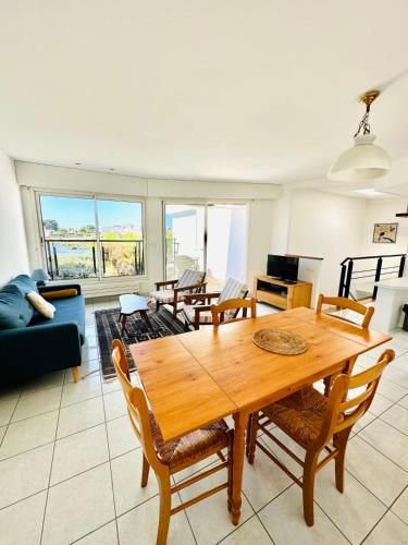 un salon avec une table et des chaises en bois dans l'établissement Charmante maison les pieds dans l'eau, à Ploemeur