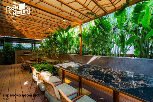 a restaurant with a counter with chairs and plants at Son&Henry Zenity District 1 in Ho Chi Minh City