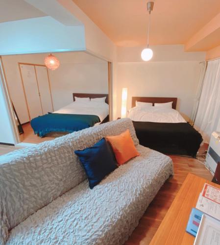 a living room with a couch and two beds at 札幌駅近 すすきの中心部 スーペリアルーム最大7名 家族やグループにお勧め 市電駅前 北海道観光食事最高立地 11歳まで子供無料 高級ベッドマットレス使用 チェックアウト11時 in Sapporo