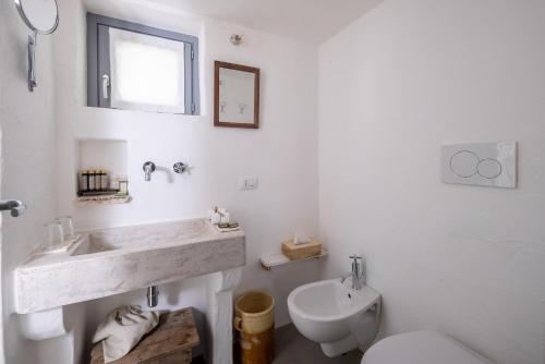 a white bathroom with a sink and a toilet at Masseria Le Torri in Polignano a Mare
