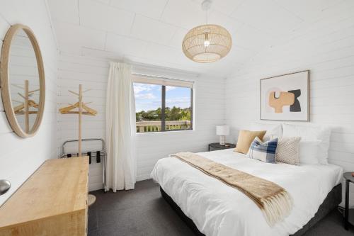 een witte slaapkamer met een bed en een raam bij Paihia Coastal 2 Bedroom Cottages in Haruru