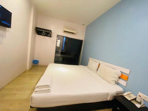 Cama blanca en habitación con teléfono en Orange Hotel Segamat en Segamat