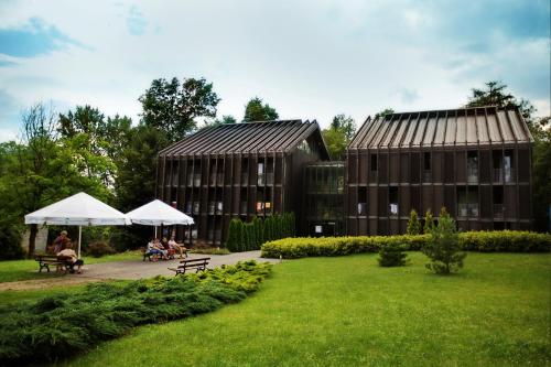 two buildings with people sitting under umbrellas in a park at Jesienna Rezydencja in Nałęczów