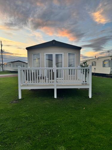 a white bench in the grass in front of a house at Bayview Bliss - Holiday Caravan in Newbiggin by the Sea - Northumberland in Newbiggin-by-the-Sea