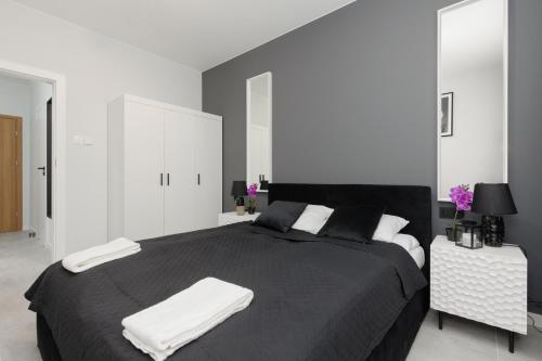 una camera da letto con un letto nero con due asciugamani di Apartment with Balcony by the Park in Łódź by Renters Prestige a Łódź