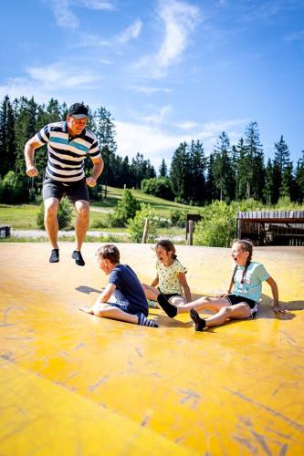 a man jumping in the water with three children sitting on the ground at KORZO LIPNO C in Lipno nad Vltavou