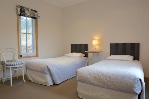 1 dormitorio con 2 camas, silla y ventana en Riversdale Estate Cottages, en Cambridge