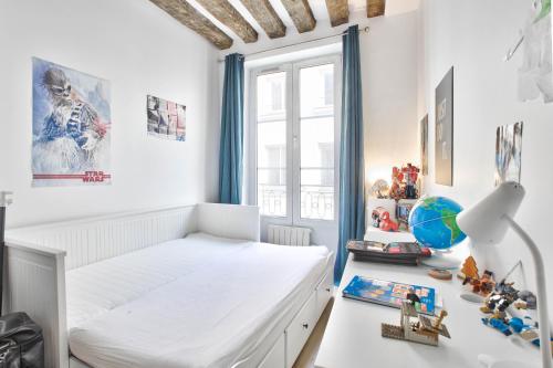 une chambre blanche avec un lit et un bureau dans l'établissement Charme et Chic du Marais, à Paris