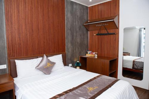 a bedroom with a bed with white sheets and wooden walls at Tam Đảo Hotel in Tam Ðảo