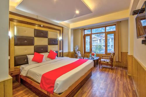 a bedroom with a large bed with red pillows at Hotel Vijayant in Manāli